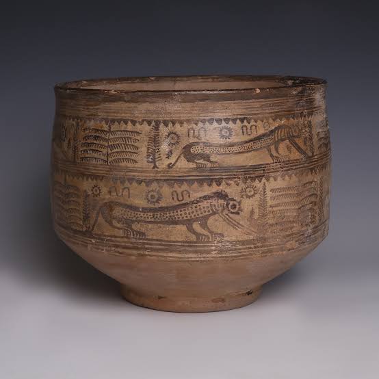Wide clay pot painted in brown with bands of striding animals, plants and sun symbols